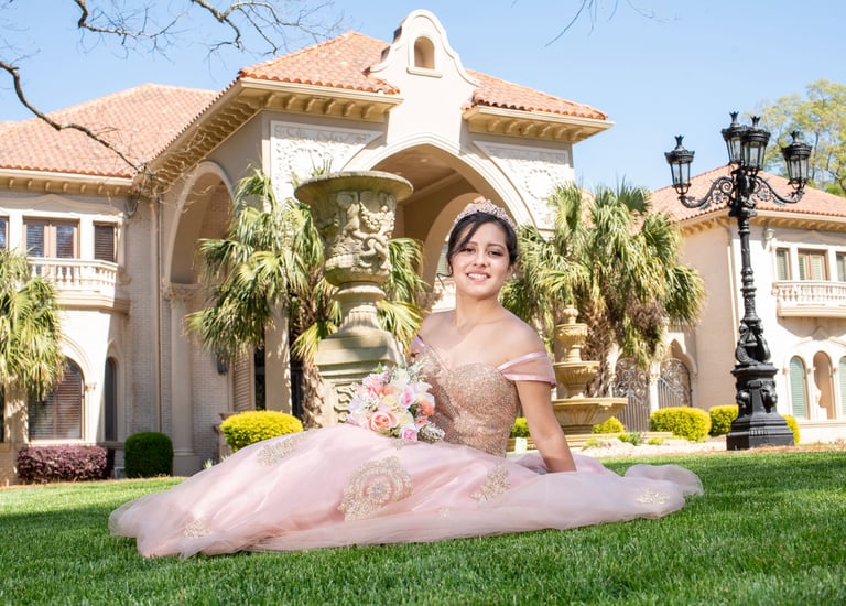 Elegant Quinceañera in a pink dress sitting on the grass