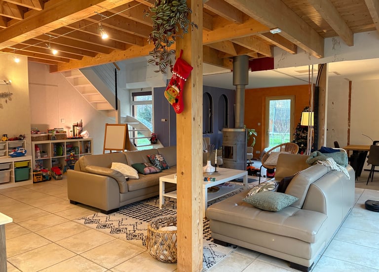 Pièce de vie avec charpente en bois apparente et canapé en cuir