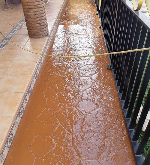 Renovación de suelo de hormigón con acabado en resina de color tostado en un patio .