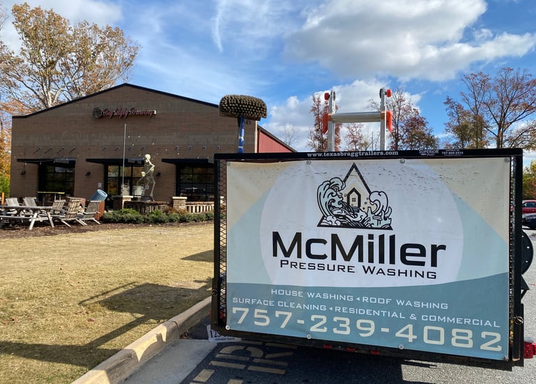 McMiller Pressure Washing trailer parked in front of a commercial brick building for exterior cleaning services.