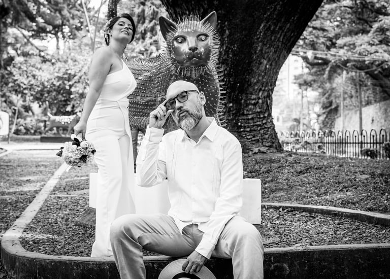 Pareja de novios el dia de su boda, posando junto a una escultura