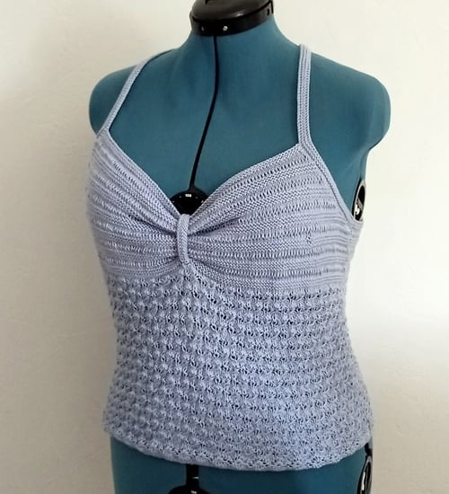 Top d'été tricoté avec un fil coton bleu clair il est posé sur un mannequin de couturière 