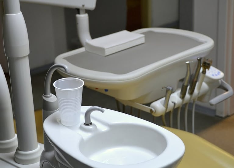 Professional dental chair station with a white rinsing sink and plastic water cup.
