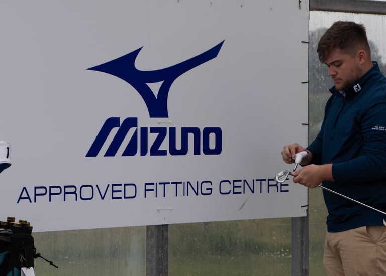 A golf coach in Aberdeen is adjusting a golf club during a custom fitting session for a client at an approved fitting centre