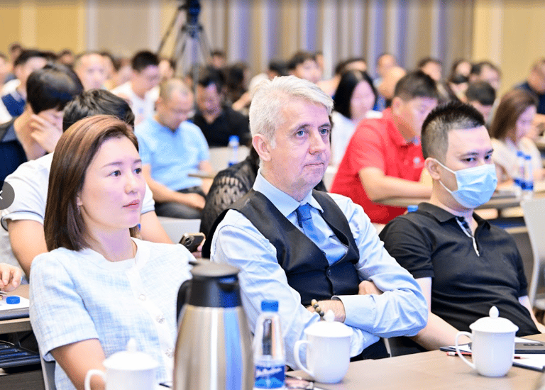 Professional attendees listening intently at a business conference seminar in an auditorium.