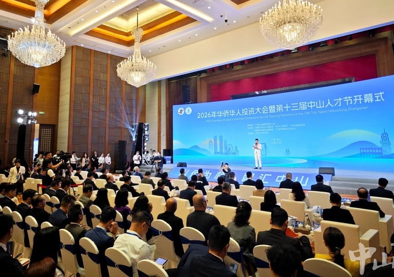 Professional business conference in Zhongshan with attendees seated facing a large blue digital stage display.