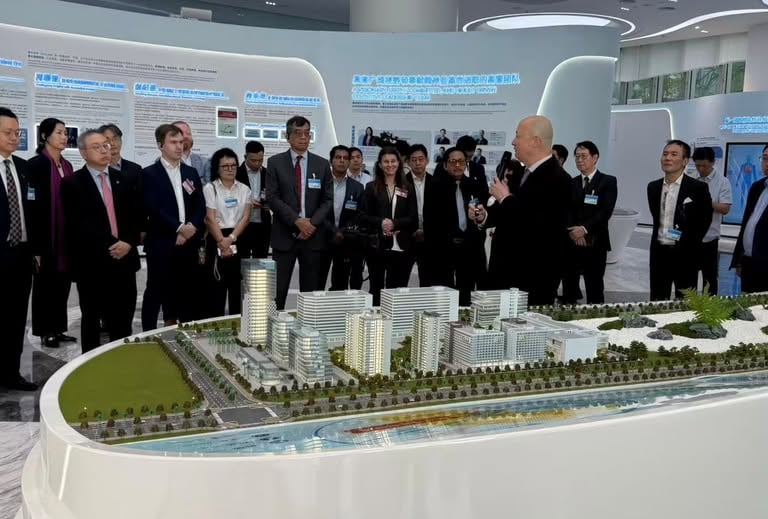 A group of business professionals viewing a detailed architectural 3D scale model of a modern city development.