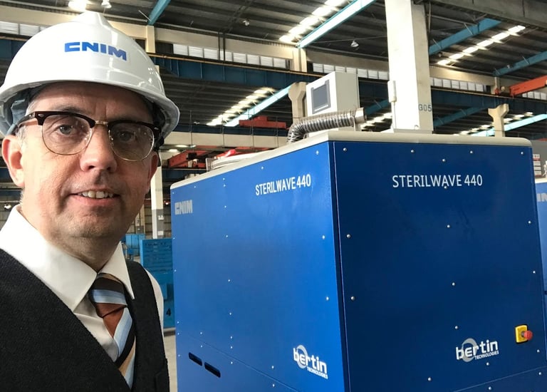 Engineer in a hard hat standing by a Bertin Sterilwave 440 medical waste treatment machine.