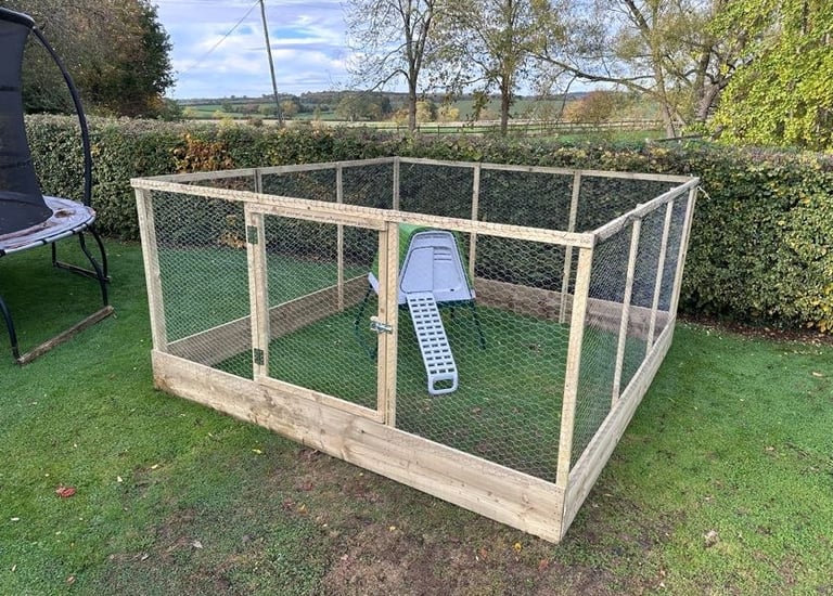 Large wooden chicken run with wire mesh and a small coop on a green lawn.