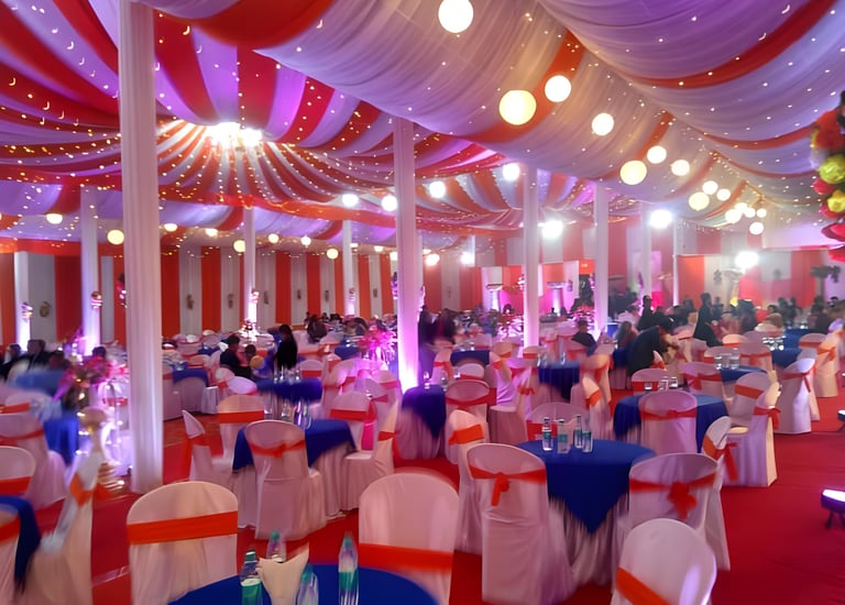 "Large indoor event space decorated with red and white drapes, hanging lights, round tables.