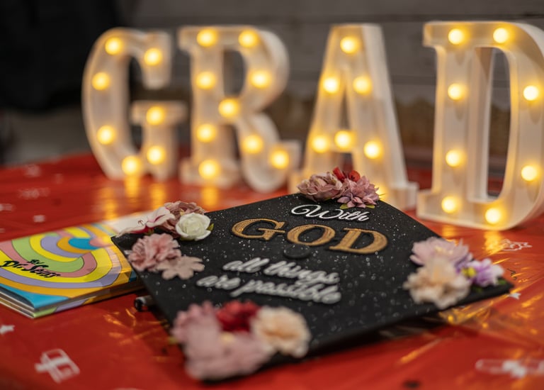 Close up image of a graduation cap with "With God all things are possible" written on the top