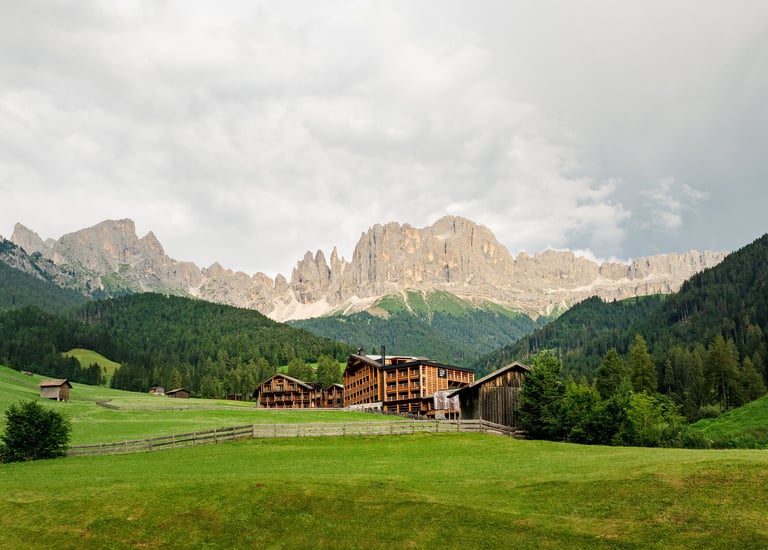 Drone photography of Cyprianerhof Dolomit Resort with the Rosengarten mountain in the background.