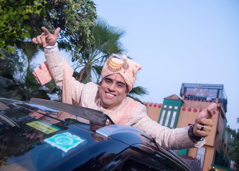 Groom in turban leaning out of a car sun roof and dancing on his wedding day..