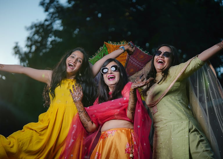 Three women laughing and posing on bride mehndi day