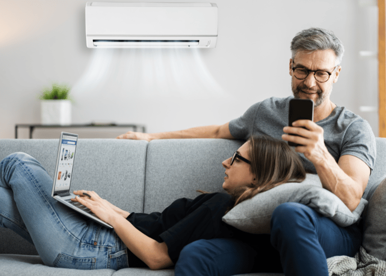 casal no sofa tranquilo controlando a temperatura do ar condicionado pelo celular