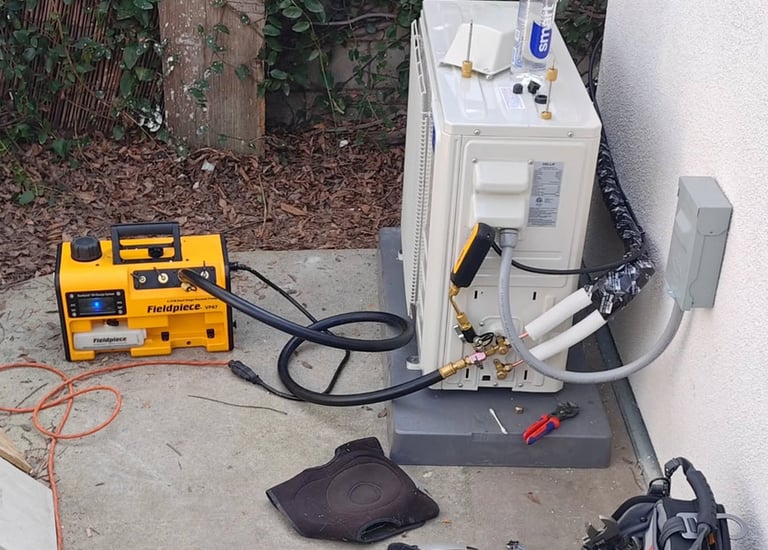 An HVAC technician installs an outdoor ductless mini split air conditioner unit using a Fieldpiece vacuum pump.