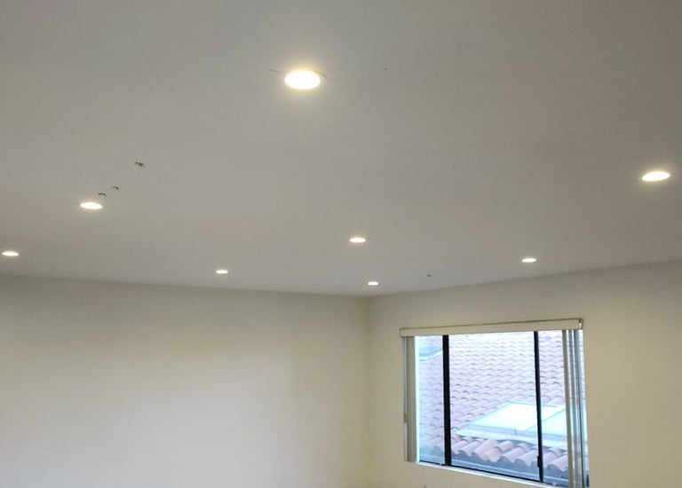 Modern white room featuring installed recessed LED ceiling lights and light wood flooring.