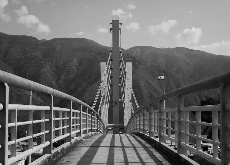 a suspension bridge leading towards some mountains