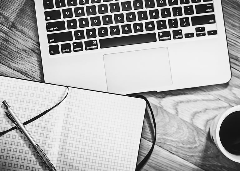 a laptop, notebook, pen and a cup of coffee