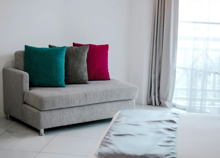 A sofa with three colored cushions on it standing in the corner of a room
