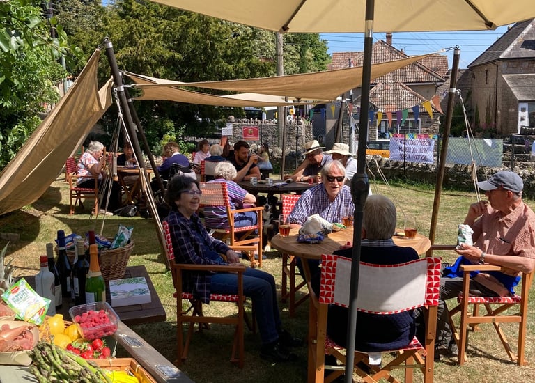 People enjoying sitting in the Westbury-sub-Mendip Community Shop garden in the sunshine