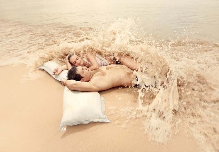 a man and woman laying on a pillow on Samui beach