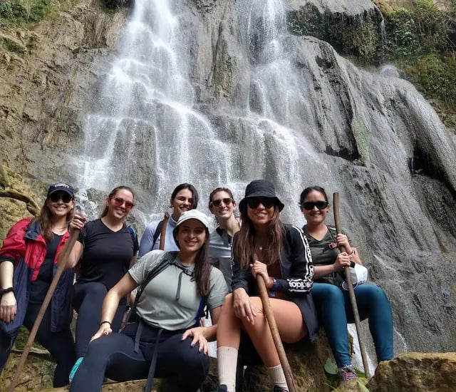 a group of people standing around a waterfall
