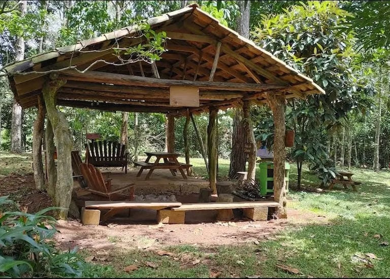 a wooden gazeboar with a bench and chairs