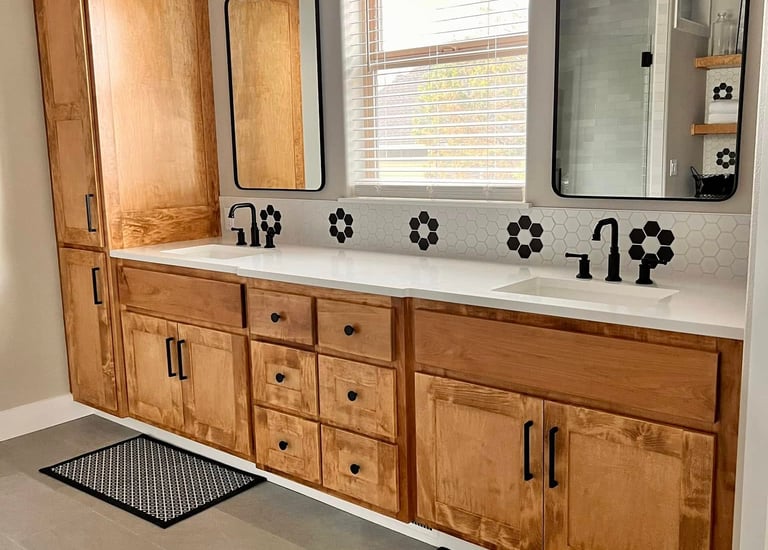 Modern master bathroom with double wood vanity, white quartz counters, and black hexagon tile accents.