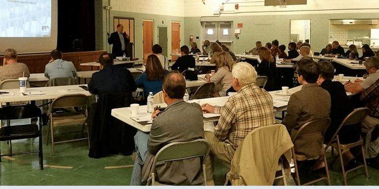 a group of people sitting at tables in a room during workshop