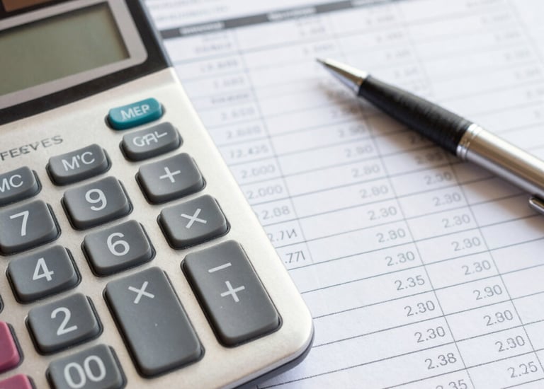 Close-up of a financial ledger and calculator on a wooden desk, symbolizing expense management.