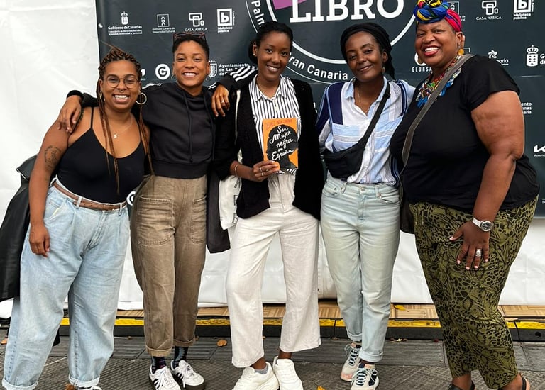 Un grupo de mujeres afro de pie frente a una pancarta posando para la foto