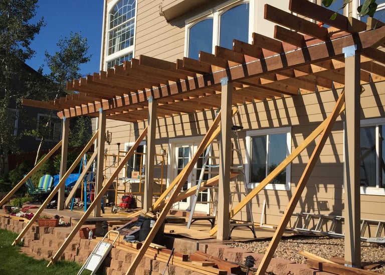 Angled view of a large residential wood deck project mid-construction with temporary support bracing.