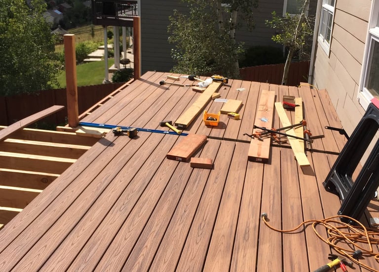 Progress shot of laying down durable composite deck boards on new joists during a backyard build.