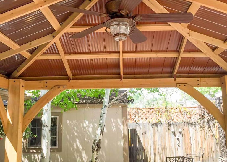 Finished wood framing and a ceiling fan inside a custom backyard pergola in littleton