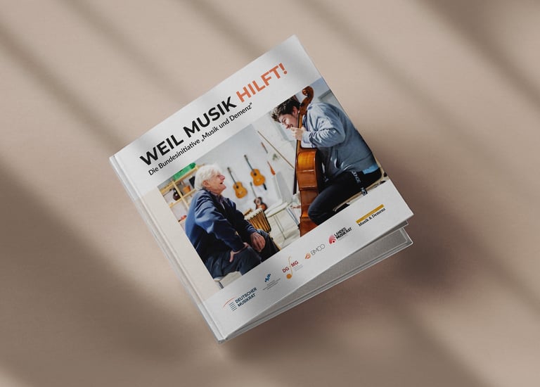 Gedruckte Broschüre „weil Musik hilft” liegt auf beigem Boden mit Schattierungen