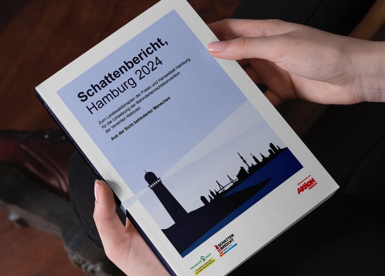 Mann hält gedruckte Broschüre des Schattenbericht Hamburg und schaut aufs Deckblatt