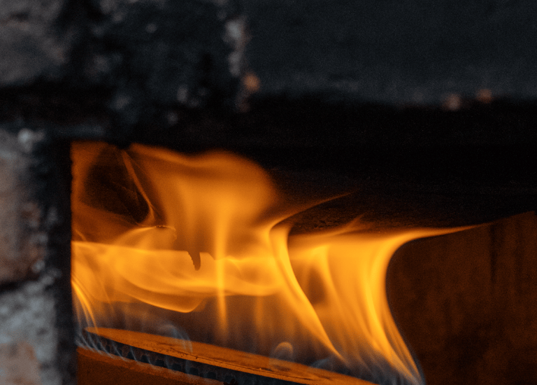 Golden flames from a gas burner heating a stone pizza oven or brick furnace.