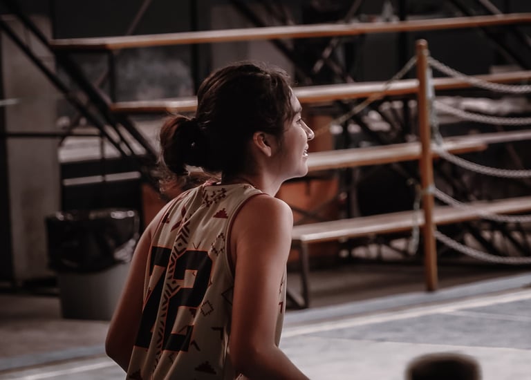 Young female basketball player in a patterned jersey smiles during a game on an indoor court.