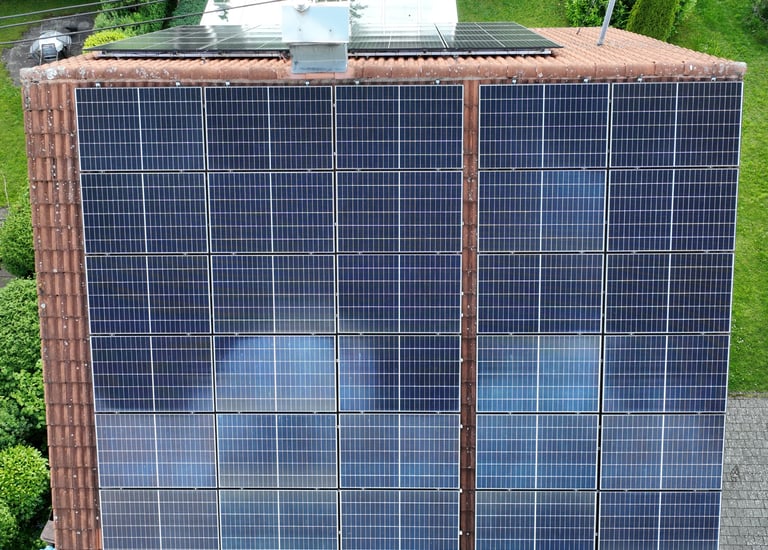 Aerial view of a residential rooftop with solar panels installed on orange tiles for renewable energy.