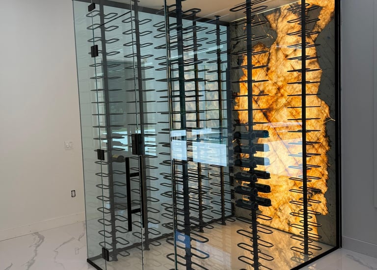 Modern glass wine cellar with black metal racks and a striking backlit onyx or marble accent wall for elegant wine storage.