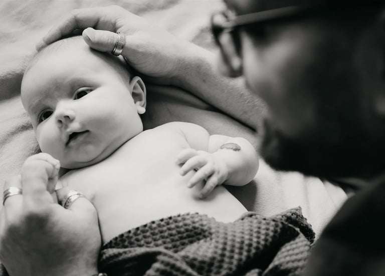Papa protège tendrement son bébé avec ses mains – photo naissance à domicile dans le Gard