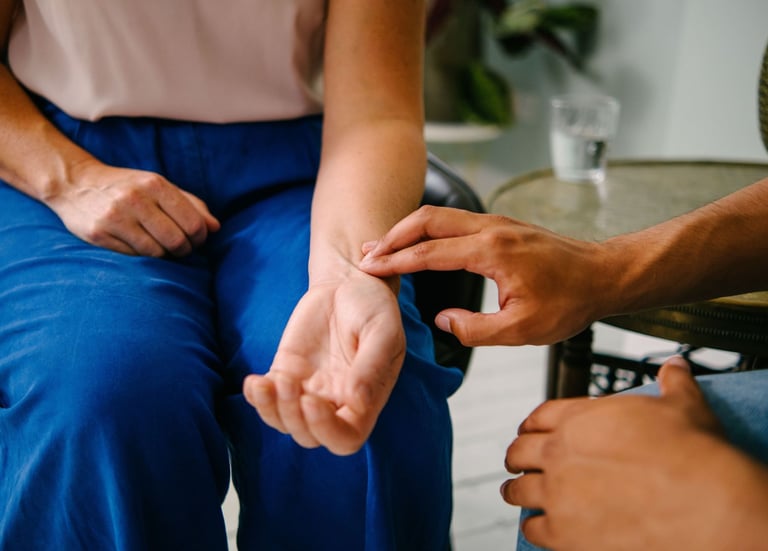 A healthcare professional checking a patient's pulse by hand on their wrist for a medical heart rate monitor check.