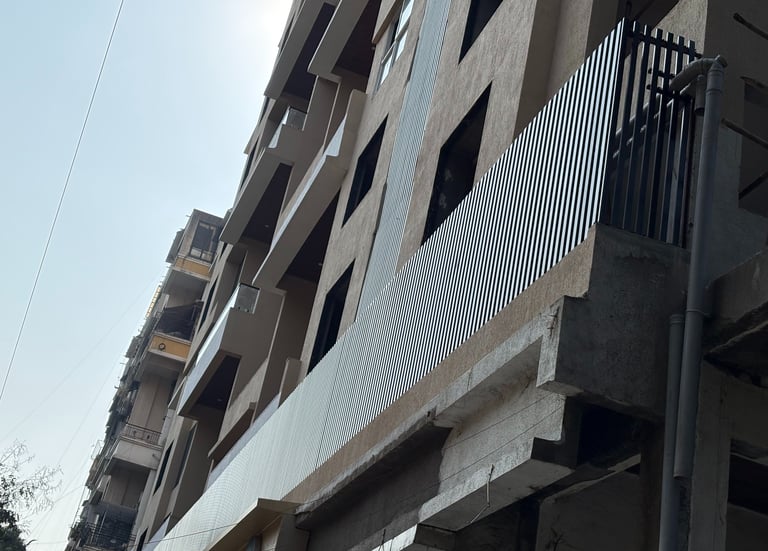 Low angle view of a modern apartment building under construction with metal balcony louvers.