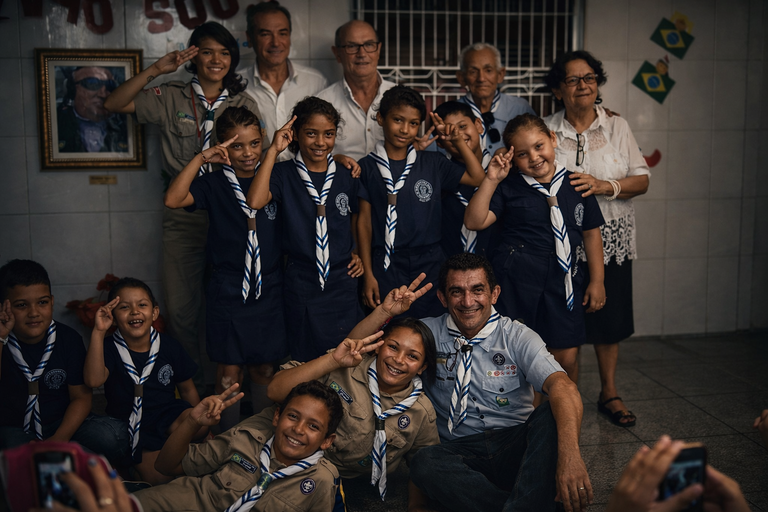 A group of Brazilian scouts in blue uniforms posing for a group photo with leaders and elders.