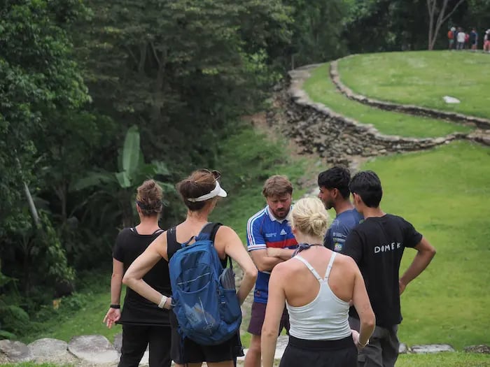 Hikers with backpacks taking a guided tour of the stone ruins at Ciudad Perdida in Colombia.