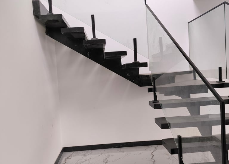 Bespoke mono-stringer steel staircase with tempered glass balustrade and slim profile.