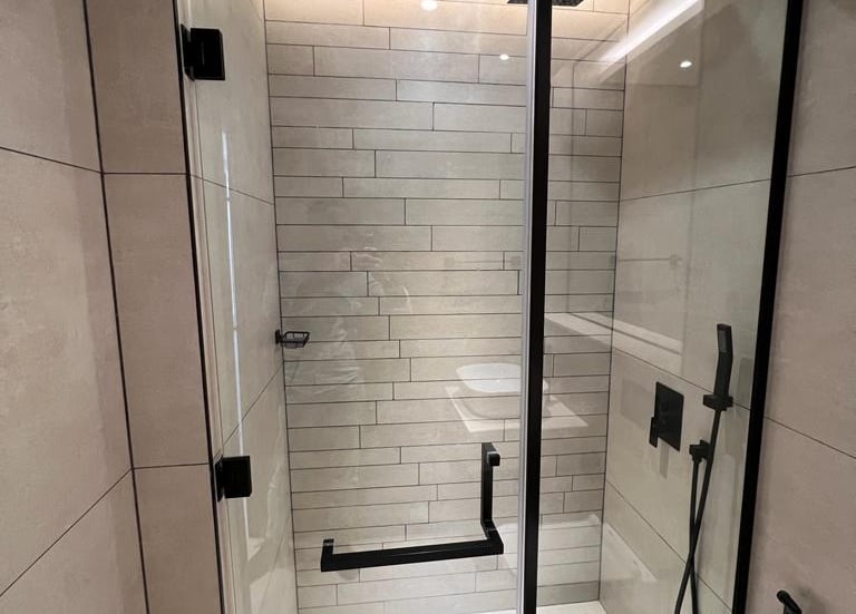 Modern walk-in shower partition with matte black stainless steel frame and tempered glass.
