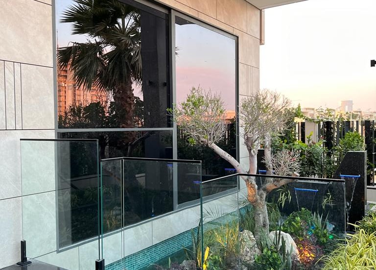 Frameless glass garden fencing with stainless steel spigots bordering a green lawn.
