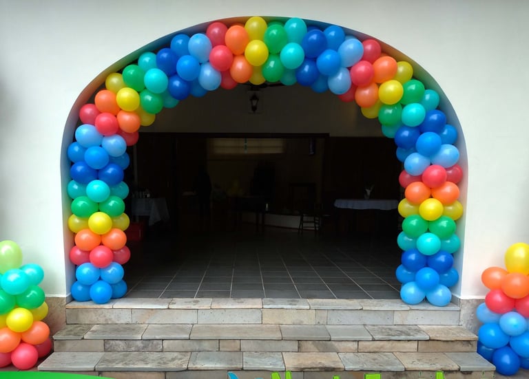 Arco de balões colorido na entrada de aniversário, criando ambiente alegre e acolhedor.